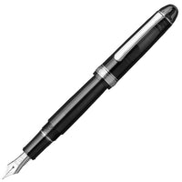 A black resin fountain pen with rhodium trim and a gold nib, shown uncapped.